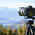 DSLR camera on tripod capturing a stunning mountain view on a clear day.
