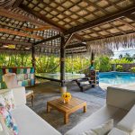 Tropical outdoor patio featuring a cabana, seating area, and swimming pool, perfect for luxury relaxation.