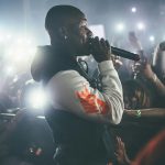 Dynamic shot of a rapper performing live in a crowded nightclub with vibrant lights.