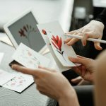 Artists discussing floral tattoo designs using sketches and a digital tablet in a studio.